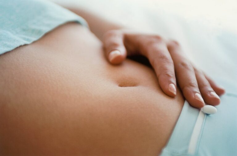 Femme touchant doucement son ventre pour détecter des signes précoces de grossesse