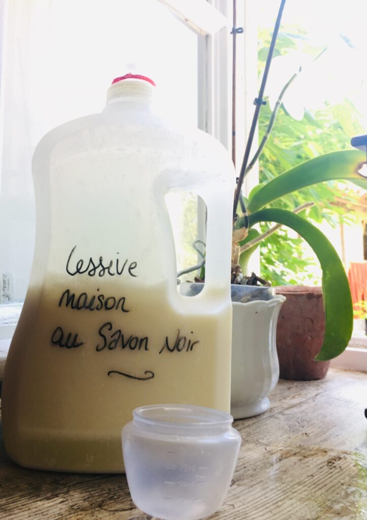 Pot de lessive maison au savon noir avec des ingrédients en arrière-plan