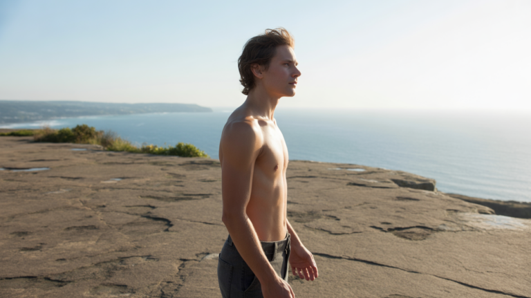 Personne debout sur une falaise au lever du soleil regardant l’horizon avec une posture confiante et naturelle.